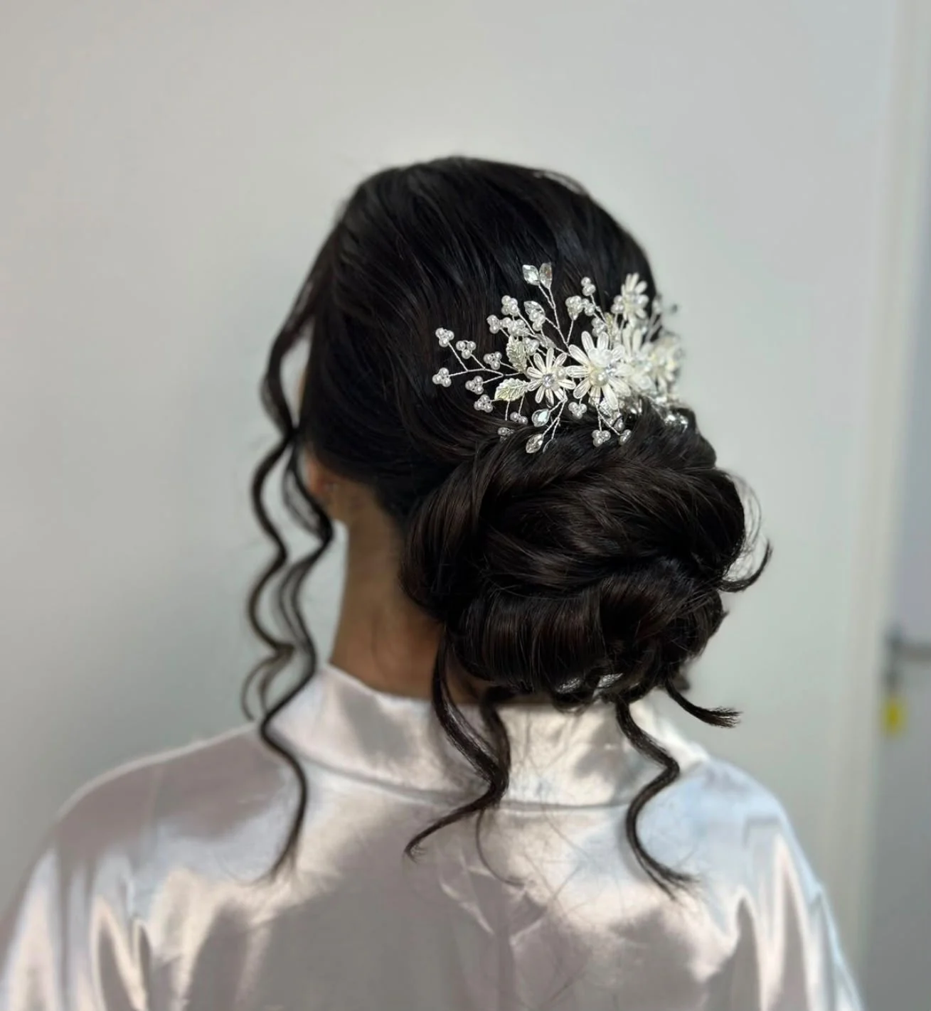 Coque baixo com acessório floral e mechas soltas